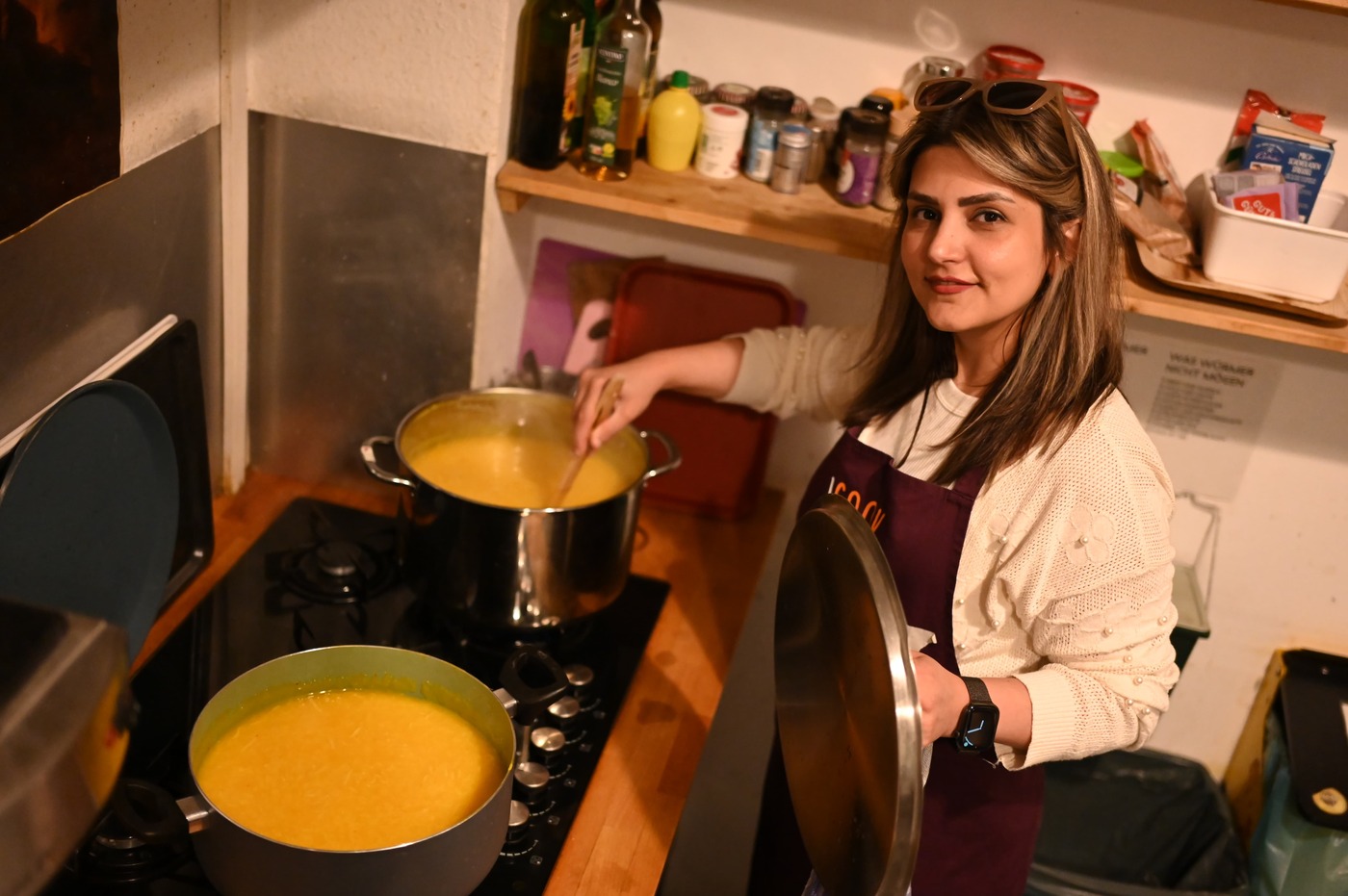 Über den Tellerrand Hamburg e. V., Frau am Herd mit zwei großen Töpfen Suppe